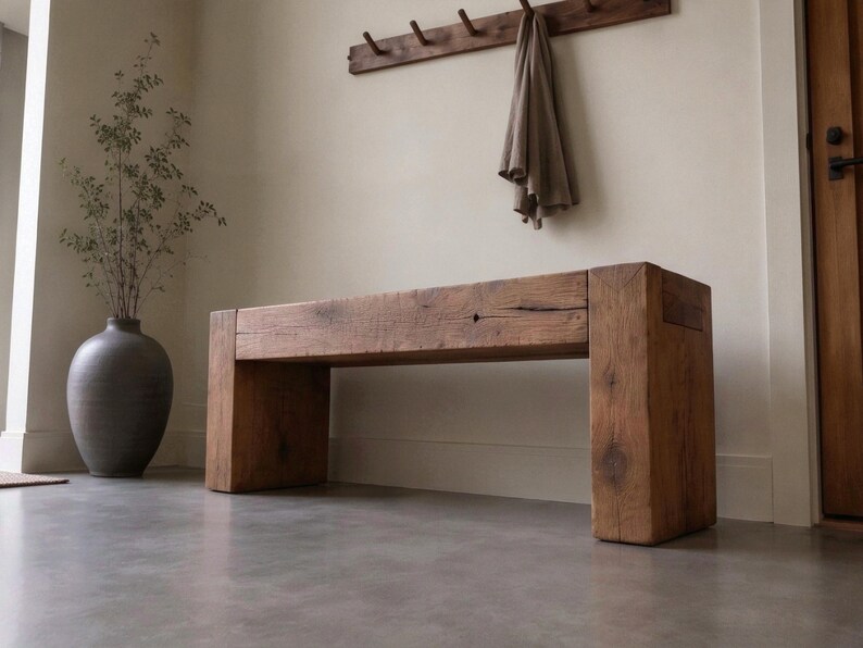 May include: A rectangular bench constructed from thick, reclaimed brown timber with a visible wood grain and natural knots. The bench features a sturdy, block-style design with two wide vertical supports and a thick horizontal seat surface.
