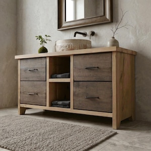 May include: A wooden bathroom vanity unit with a light-coloured countertop and dark-stained drawer fronts. The unit has two sets of drawers, an open shelf, and a stone sink. A mirror hangs above the vanity, and a rug is on the floor.