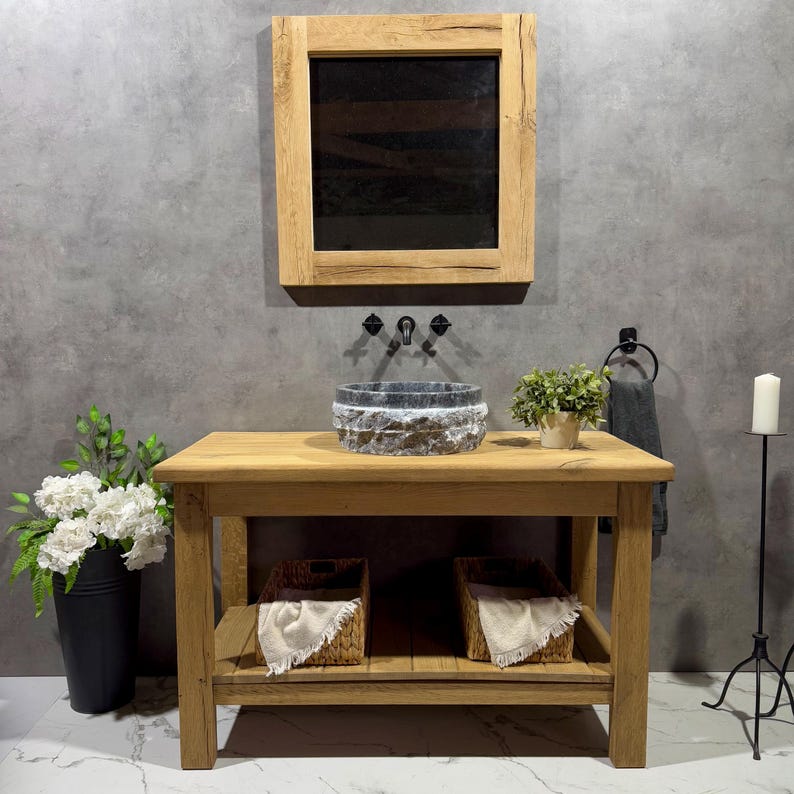 May include: A rustic wooden bathroom vanity with a stone sink, two woven baskets, and a framed mirror above. The vanity has a shelf and is made of reclaimed wood.