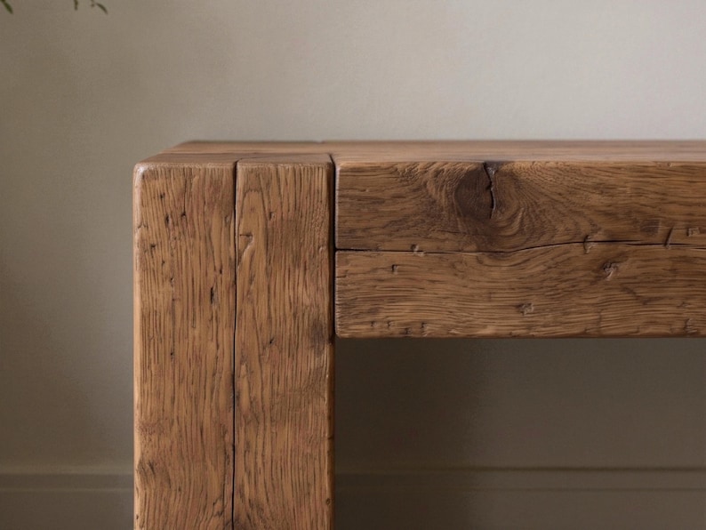 May include: A rectangular wooden table featuring a thick, block-style leg and a horizontal tabletop. The wood displays a natural medium-brown tone with visible grain patterns, deep vertical fissures, and a prominent knot on the front surface.