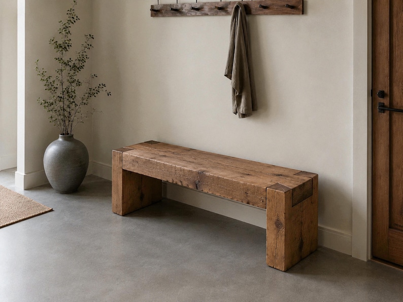 May include: A rectangular wooden bench constructed from thick, reclaimed timber planks with visible grain patterns and knots. The bench features a sturdy, block-style leg design at each end, showcasing a natural, weathered brown finish throughout.