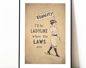 May include: A framed vintage-style print with a sepia tone. The artwork features a person holding a flag that reads "EQUALITY." Below the flag, the text reads "I'll be LADYLIE when the LAWS are." The person is wearing a hat and boots.