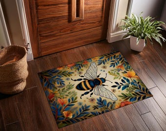 May include: Rectangular doormat featuring a large bee illustration with blue and yellow stripes, surrounded by floral and leaf designs in shades of blue, orange, and green. The background is a light beige color.