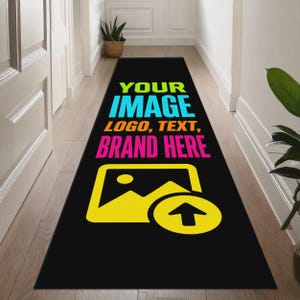 May include: A long, rectangular black runner rug featuring bright, multi-coloured text that reads YOUR IMAGE LOGO, TEXT, BRAND HERE. Below the text is a large, yellow graphic icon of a mountain landscape with an upward-pointing arrow.