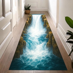 Op de afbeelding: Een rechthoekig tapijt met een watervalscène. Het ontwerp toont een trapsgewijze waterval met blauw water en rotsachtige kliffen. Het tapijt is ontworpen om een illusie van diepte en natuurlijke schoonheid te creëren.
