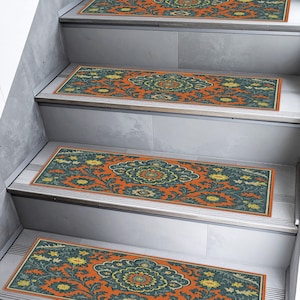 May include: Orange and teal stair treads with a floral pattern. The treads are rectangular and feature a central medallion design with intricate detailing. The stair treads are placed on a set of gray stairs.