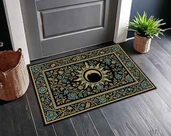 Könnte beinhalten: Schwarze rechteckige Fußmatte mit floralem und himmlischem Design. Die Matte zeigt ein zentrales Sonnen- und Mondmotiv, umgeben von türkisfarbenen und goldenen Blumenmustern auf schwarzem Hintergrund. Der Rand ist goldfarben. Ein dekorativer Akzent für einen Hauseingang.