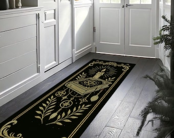 May include: Black rectangular rug with a gold design featuring a candle, book, and celestial symbols. The rug has a decorative border and is placed on a dark wood floor. The design includes a pentagram and other mystical elements.