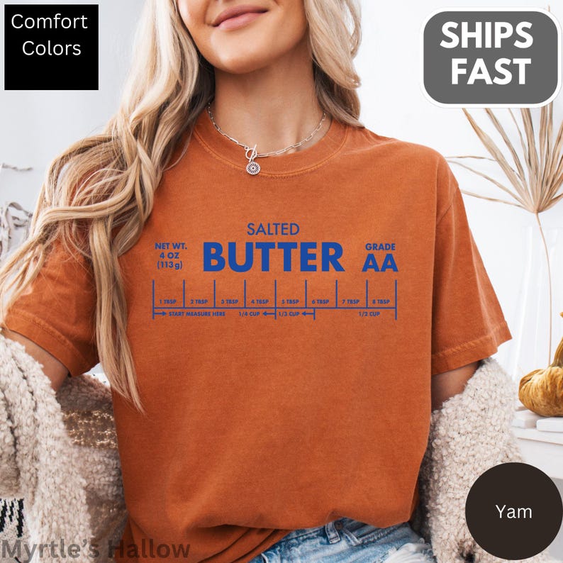 A woman wearing an orange t-shirt with a graphic design of a salted butter recipe.