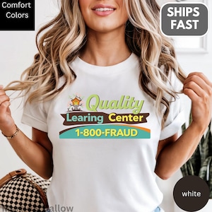May include: White t-shirt with the text "Quality Learing Center" and the phone number 1-800-FRAUD in green, brown, and teal. The shirt also has the words "Comfort Colors" and "Ships Fast" in the corners.