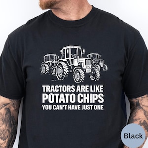 Puede incluir: Camiseta negra con un diseño blanco de tres tractores. El texto en la camiseta dice: "LOS TRACTORES SON COMO LAS PATATAS FRITAS, NO PUEDES TENER SÓLO UNA."