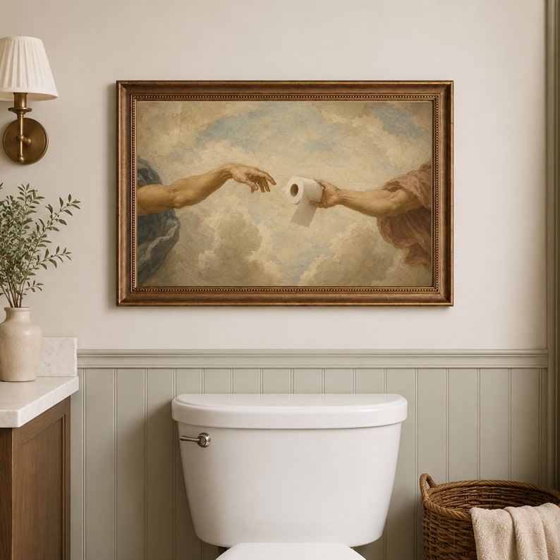 a bathroom with a framed painting of two hands reaching towards a roll of toilet paper hanging above a white toilet.