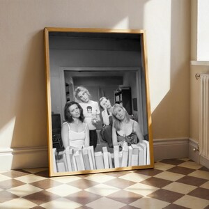 a framed black and white photograph of four people posing together in a room with a checkered floor.