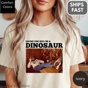 A woman wearing a white t-shirt with a graphic design featuring a man sitting on a couch.
