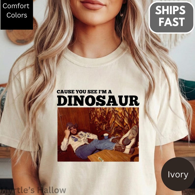 A woman wearing a white t-shirt with a graphic design featuring a man sitting on a couch.