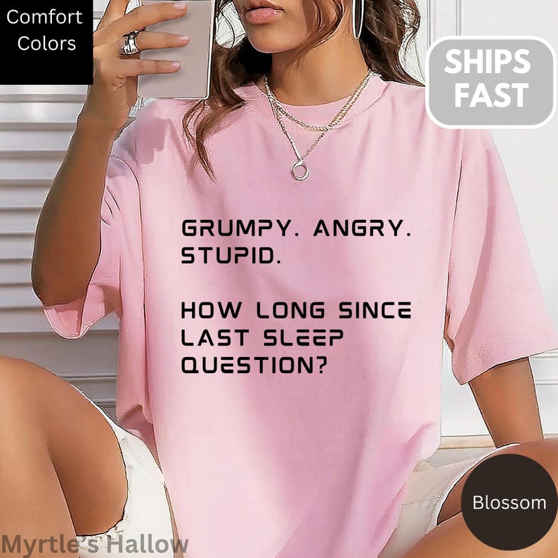 A person wearing a pink t-shirt with text printed on it, posing for a photo.