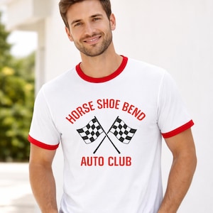 May include: White t-shirt with red trim featuring the text "HORSE SHOE BEND AUTO CLUB" in red, along with two crossed checkered flags. The shirt has a classic ringer style with a red collar and sleeve cuffs.