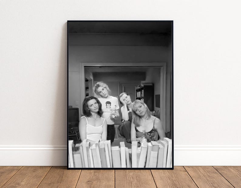 A black and white photograph of four people posing together in a room with bookshelves in the background.