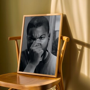 a wooden chair with a framed black and white photograph of a man covering his mouth with his hand.