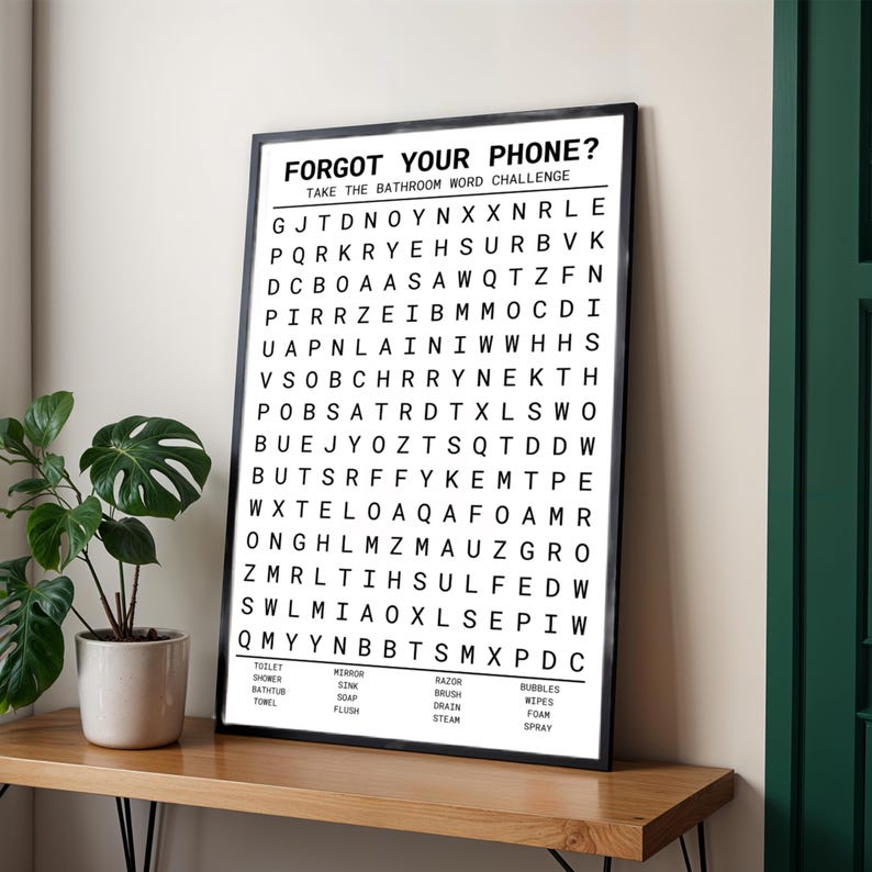 a poster titled "Forget Your Phone? Take the Bathroom Word Challenge" with a list of words to be spelled. The poster is displayed on a wooden shelf next to a potted plant.