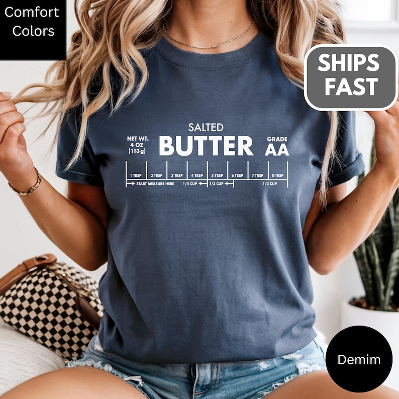 A woman wearing a blue t-shirt with a graphic design depicting the nutritional information of a salted butter product.