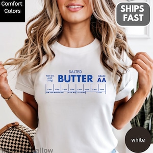 A woman wearing a white t-shirt with a blue and white design that appears to be a recipe for salted butter.