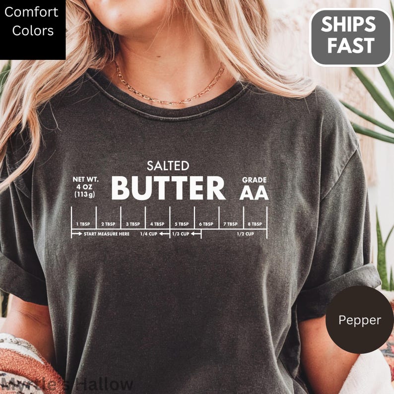 A person wearing a black t-shirt with a graphic design depicting the nutritional information and ingredients of a product called "Butter".