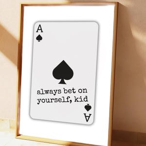 May include: Framed print featuring a white playing card, the Ace of Spades, with a large black spade symbol in the center. The text "always bet on yourself, kid" is printed below the spade symbol. The frame is gold.