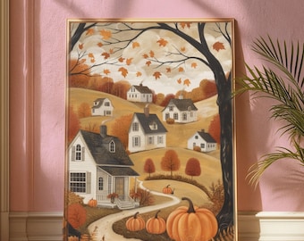 May include: A framed print depicting an autumnal village scene with white houses set in a hilly landscape. The artwork includes orange pumpkins, falling leaves, and a winding road, set against a muted sky. The colour scheme is warm, with shades of orange, brown, and beige.