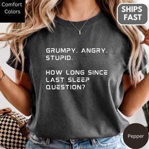 a person wearing a gray t-shirt with a humorous text printed on it.