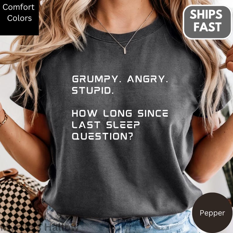 a person wearing a gray t-shirt with a humorous text printed on it.