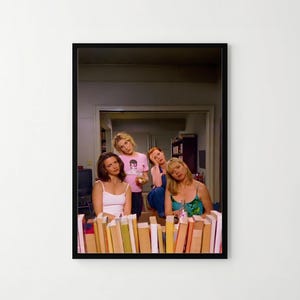 The image is a framed photograph of four women posing together in a room with bookshelves in the background.
