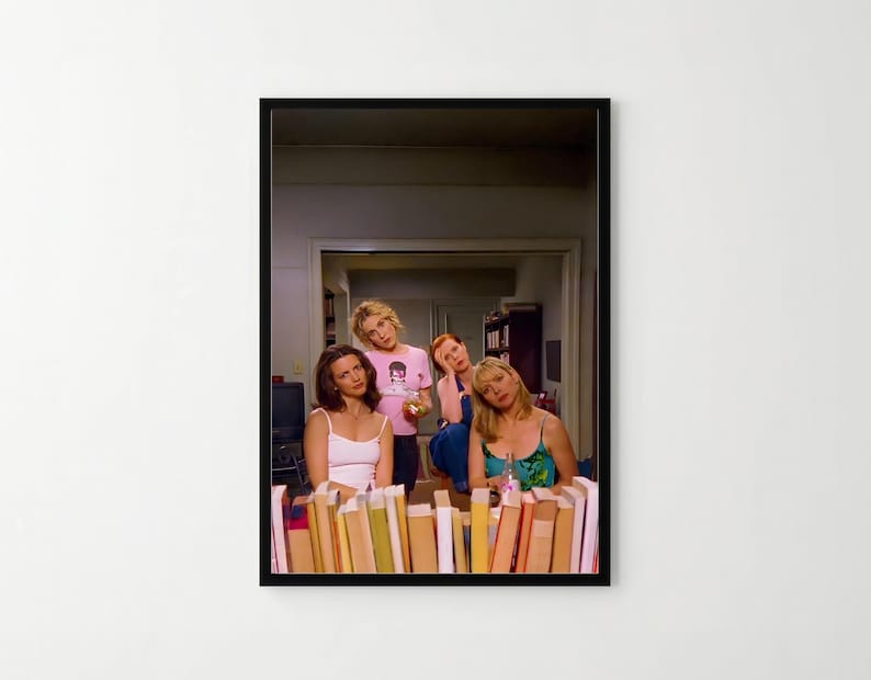 The image is a framed photograph of four women posing together in a room with bookshelves in the background.