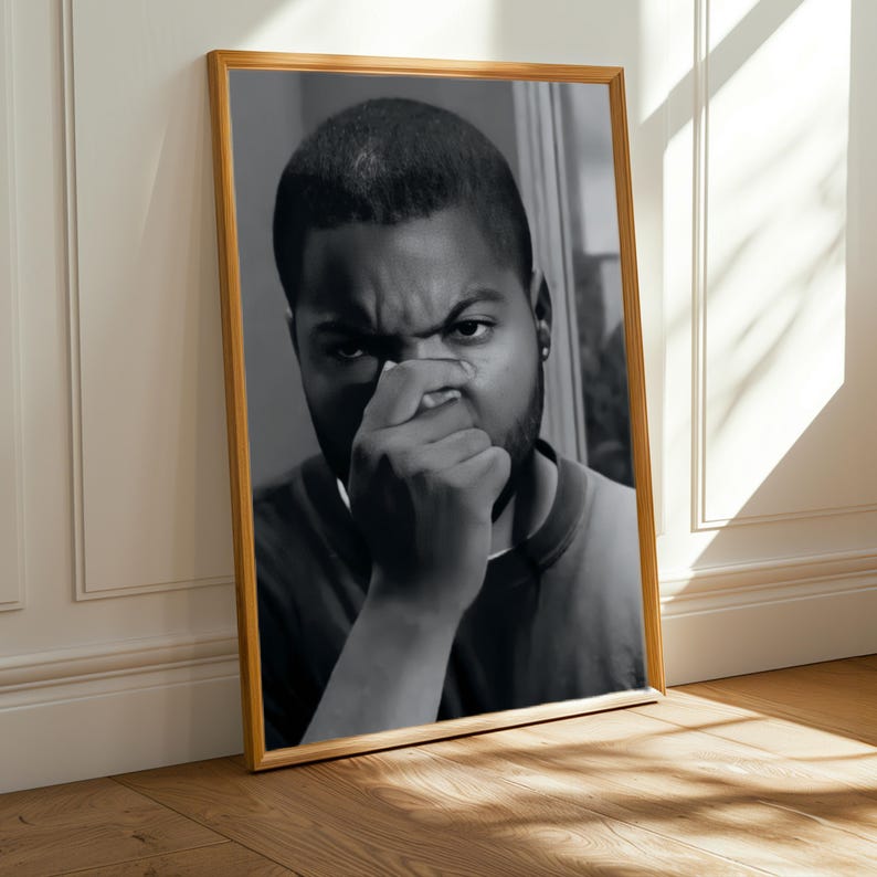a close-up of a man's face, captured in a black and white photograph, which is framed and displayed on a wooden floor.