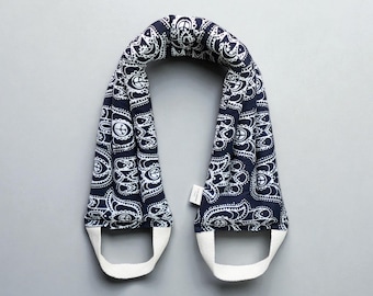 May include: A navy blue and white patterned neck wrap with white handles. The wrap features a paisley design with peace symbols. The handles are made of white fabric. The wrap is designed to be worn around the neck.