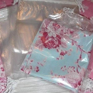 May include: A stack of clear plastic bags with drawstrings, some of the bags have a floral print fabric inside.