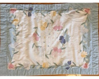 Funda de almohada vintage en tonos pastel con estampado floral y de lunares.