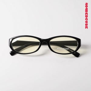 May include: Black oval-framed spectacles. The glasses feature a contemporary design, with the text "404STORE" printed on the right lens. The image also includes the text "404REDCUBE" in red.