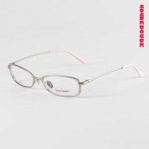 May include: Silver-framed eyeglasses with rectangular lenses and white temple tips. The glasses have a delicate, minimalist design. The text "404STORE" is printed on the frame. The text "404REDCUBE" is printed vertically on the right side.