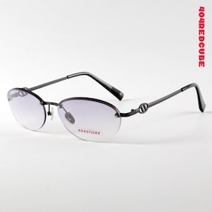 Op de afbeelding: Randloze ovale zonnebril met verloopglazen. De zwarte monturen hebben een subtiel designelement bij de slapen. De glazen lopen van licht naar donker. De tekst "404STORE" is op het glas gedrukt. Modern design.