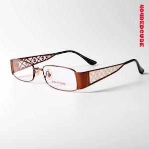 Puede incluir: Gafas rectangulares marrones con patrones geométricos decorativos en las patillas. Las monturas tienen un acabado metálico, con varillas negras y el texto "404STORE" en la lente.