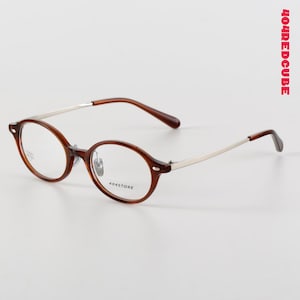 May include: Oval-shaped brown eyeglasses with silver arms. The glasses feature the text "404STORE" on the lens. The brand name "404REDCUBE" is printed vertically in red on the right side of the image.