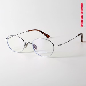 May include: Oval-lensed eyeglasses with silver frames. The temples are slender, leading to brown tortoiseshell ear pieces. The bridge and nose pads are silver. The text "404REDCUBE" is printed vertically in red on the right side.