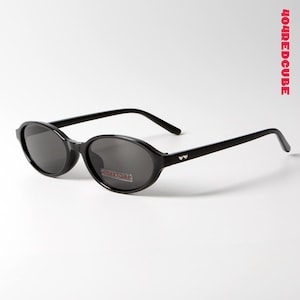 Peut inclure: Lunettes de soleil ovales noires avec des verres foncés. Les lunettes ont un design élégant avec un petit logo sur les branches. Le texte "404STORE" est visible sur un autocollant sur la lentille.