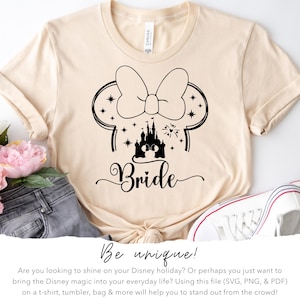 May include: Cream-colored t-shirt featuring a black graphic of Minnie Mouse ears with stars, a castle, and the word "Bride." The shirt is styled with jeans, flowers, and a white sneaker. The text "Be unique!" is also visible.