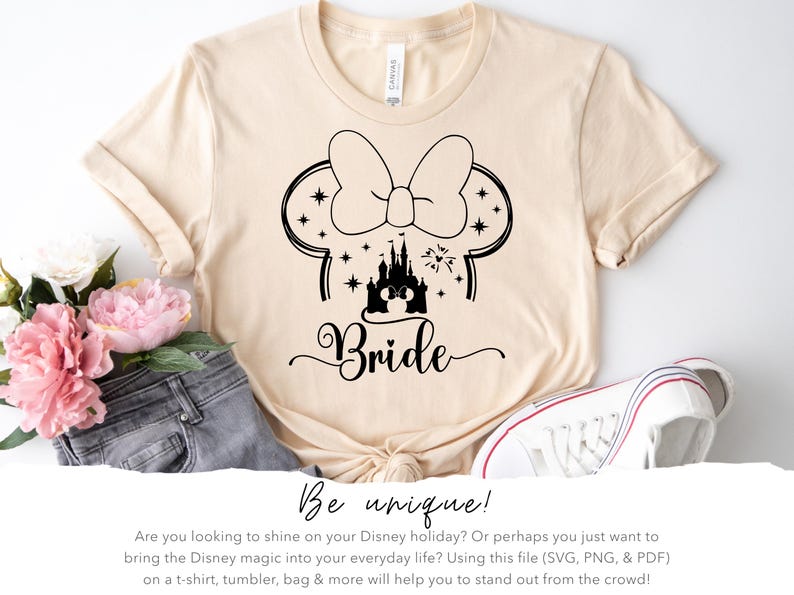 May include: Cream-colored t-shirt featuring a black graphic of Minnie Mouse ears with stars, a castle, and the word "Bride." The shirt is styled with jeans, flowers, and a white sneaker. The text "Be unique!" is also visible.