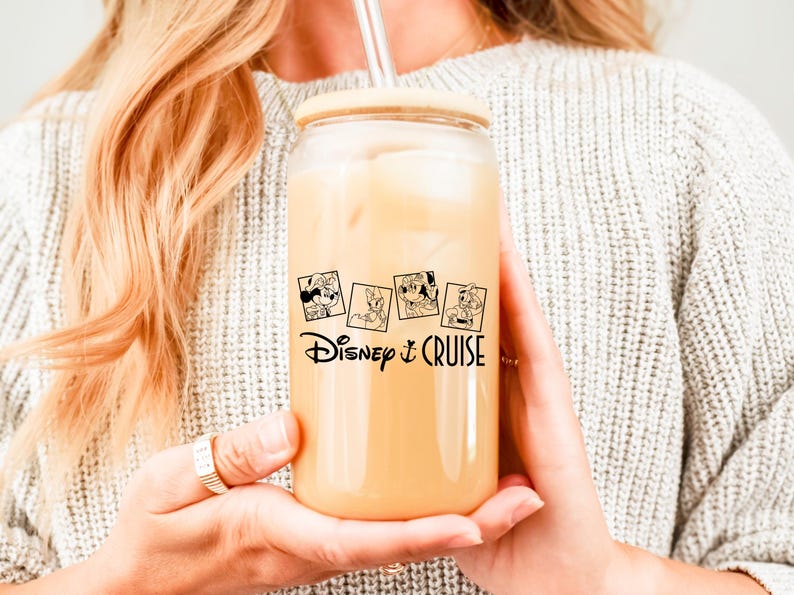May include: A clear glass tumbler with a wooden lid and a straw. The tumbler has a black and white graphic of Disney characters and the text "Disney Cruise".