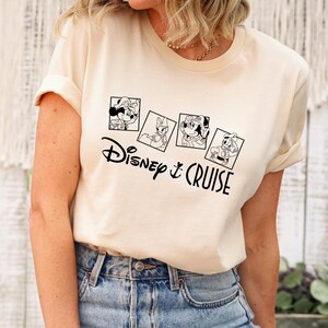 May include: A white t-shirt with a black graphic of Disney characters in picture frames. The text "Disney & Cruise" is below the frames.