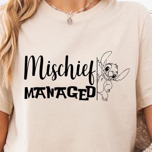 Puede incluir: Una camiseta beige claro con texto negro que dice "Mischeif Managed" y un personaje de dibujos animados en blanco y negro que asoma por el lado.