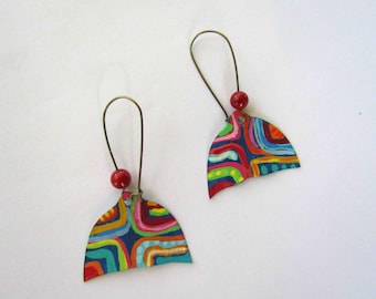 May include: A pair of colorful, abstract earrings. Each earring features a fan-shaped design with a vibrant pattern of curved lines in red, blue, green, and yellow. A small red bead hangs from a wire loop.